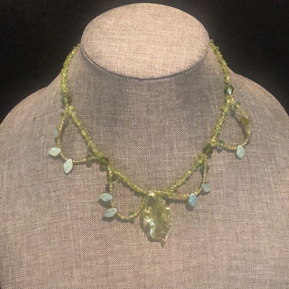 Earthy soft green necklace with green glass leaf at the center. 17” long.
